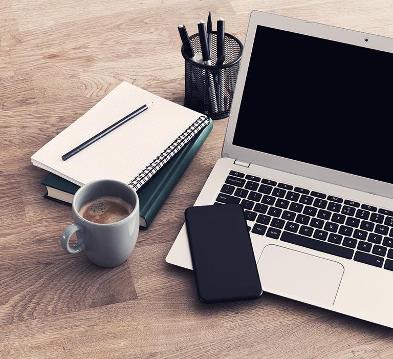Kawa, notes, telefon i laptop na drewnianym biurku